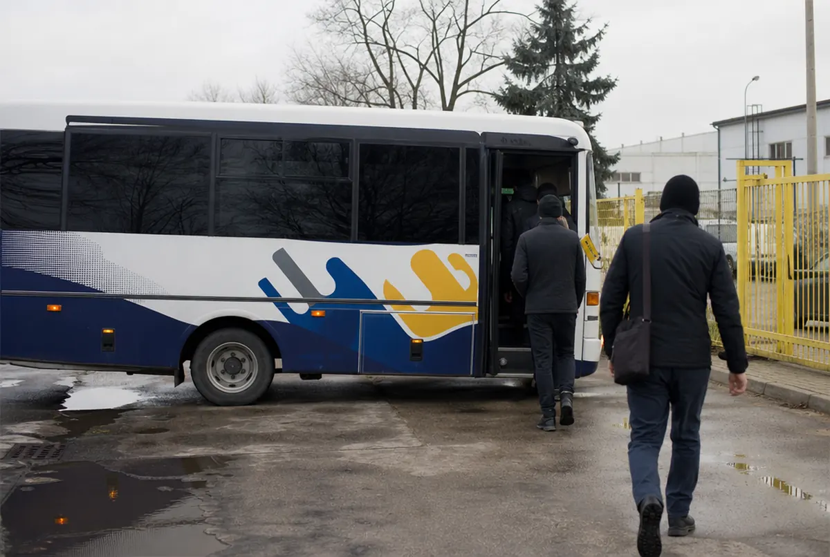 Beschrifteter Bus einer Zeitarbeitsfirma bringt Mitarbeiter zum Werk