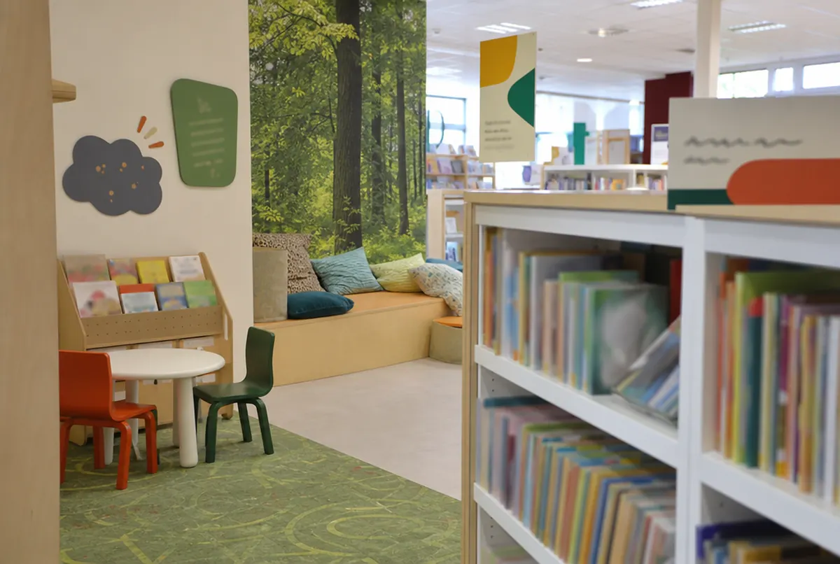 Children’s corner in a library with a wall mural and shelf signs