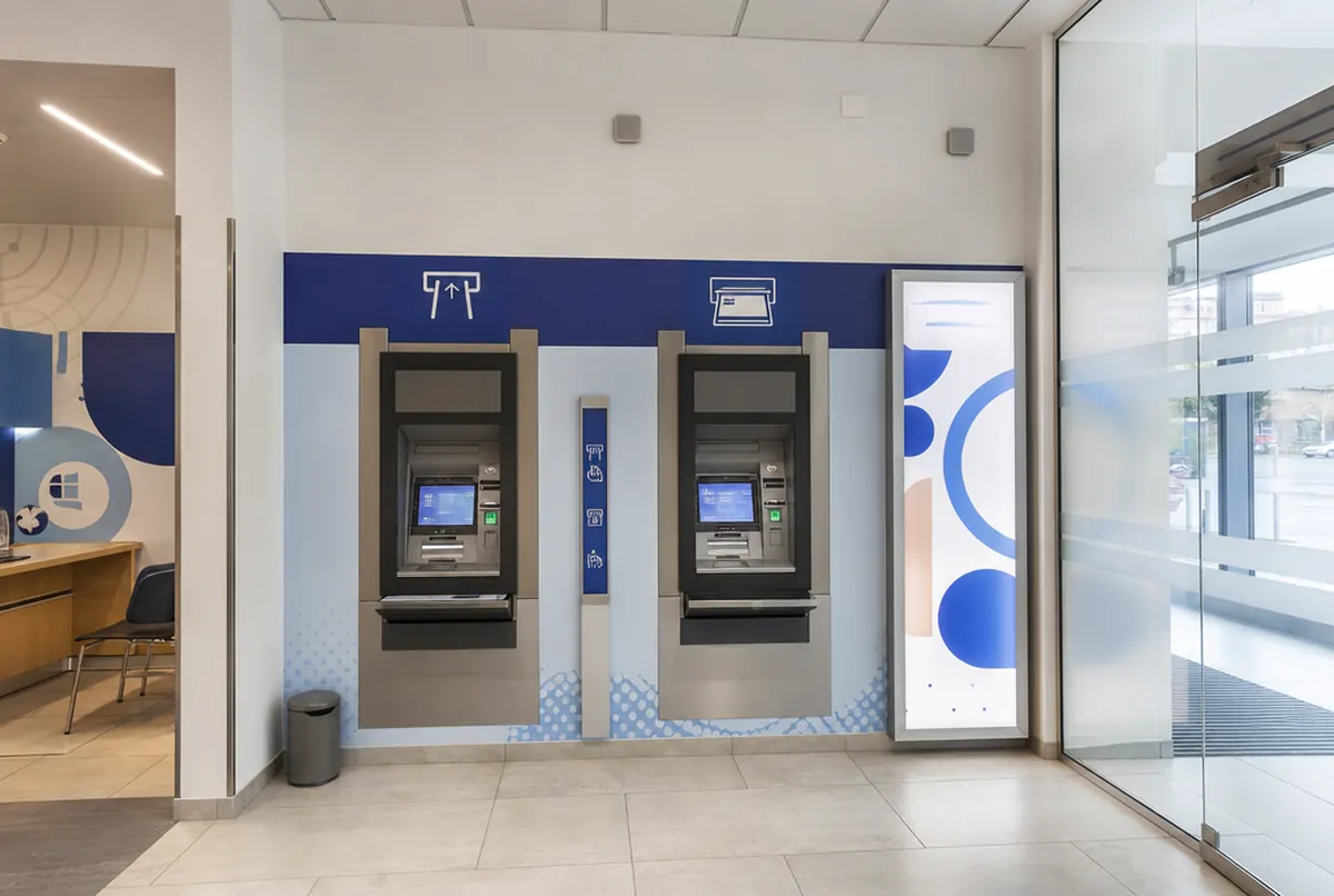 Geldautomatenbereich in einer Bankfiliale mit Beschilderung und Leuchtrahmen