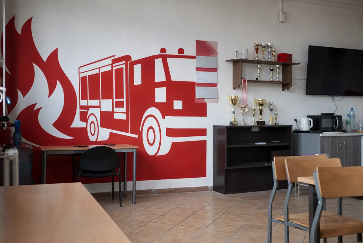 Fire station clubroom with a wall mural, trophies and a calendar