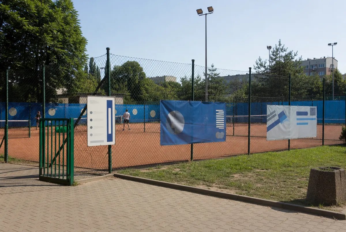 Municipal tennis courts with windscreens and banners on the fence