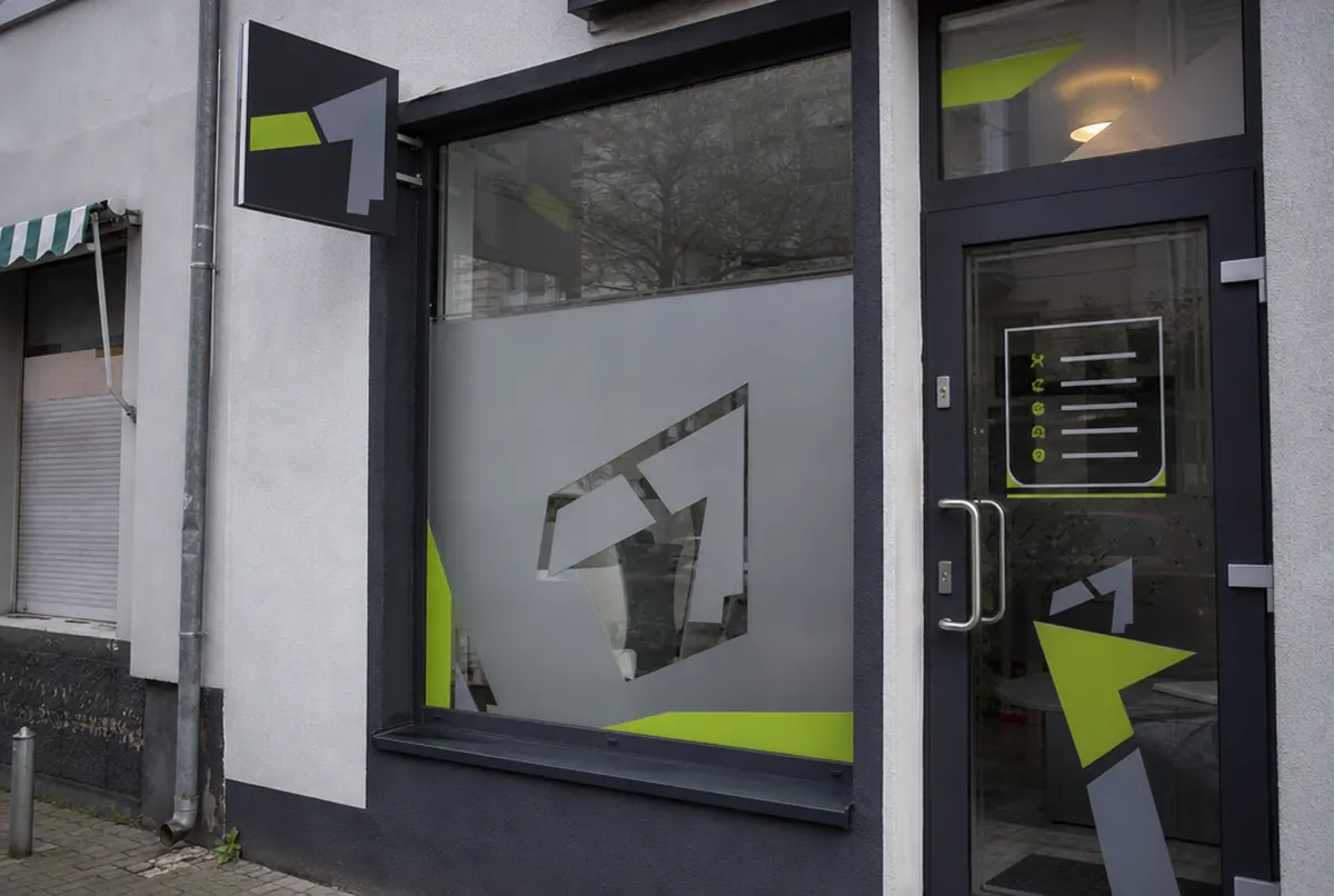 Schaufenster eines Barbershops mit Milchglasfolie mit ausgespartem Logo und Nasenschild