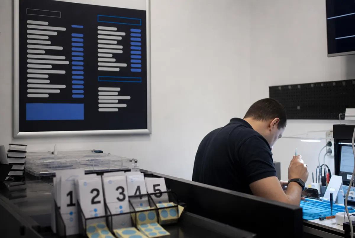 Handy-Reparatur in einem Handyladen mit Reparaturpreisliste an der Wand