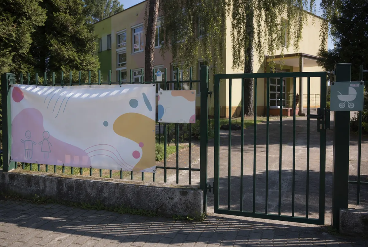Bâche d’inscription et panneau d’horaires sur la clôture d’une crèche