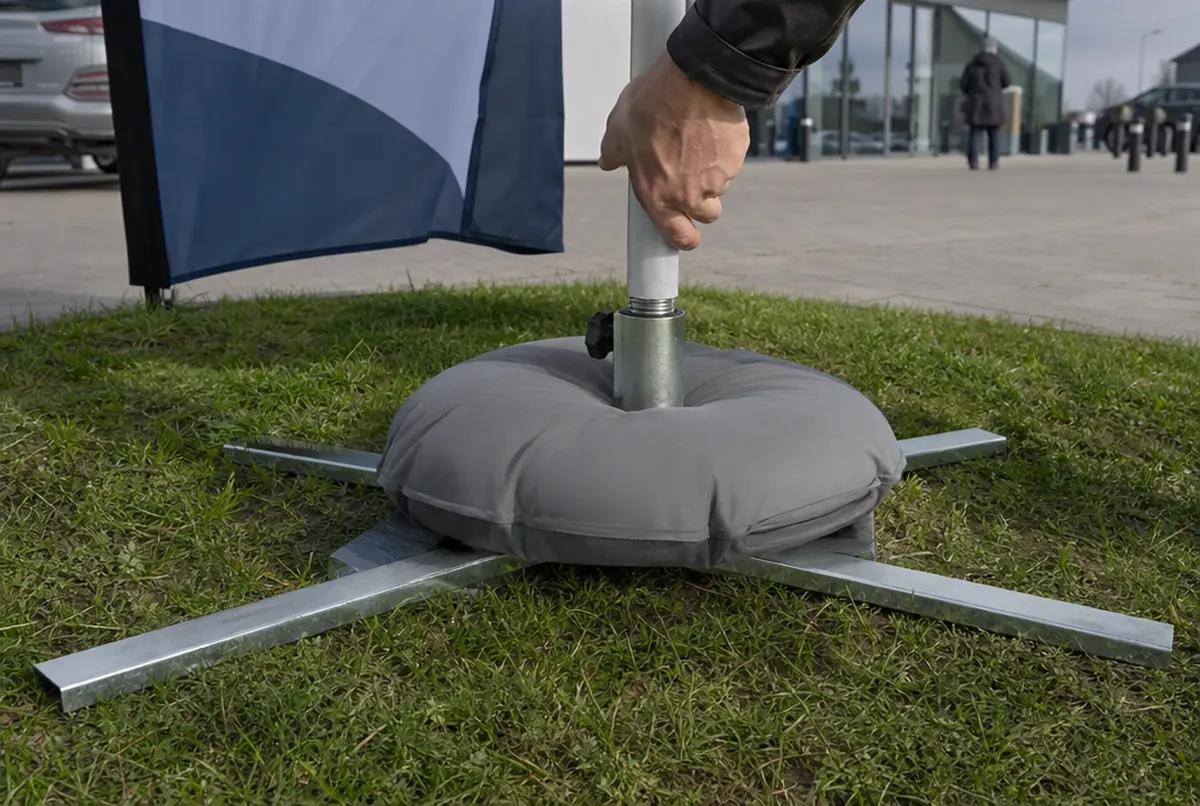 Weighted cross base and feather flag pole on grass