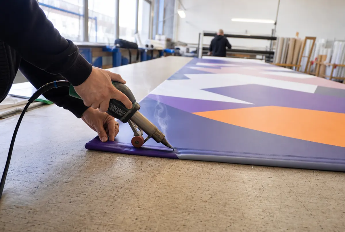 Welding the edge of a long banner on a finishing table