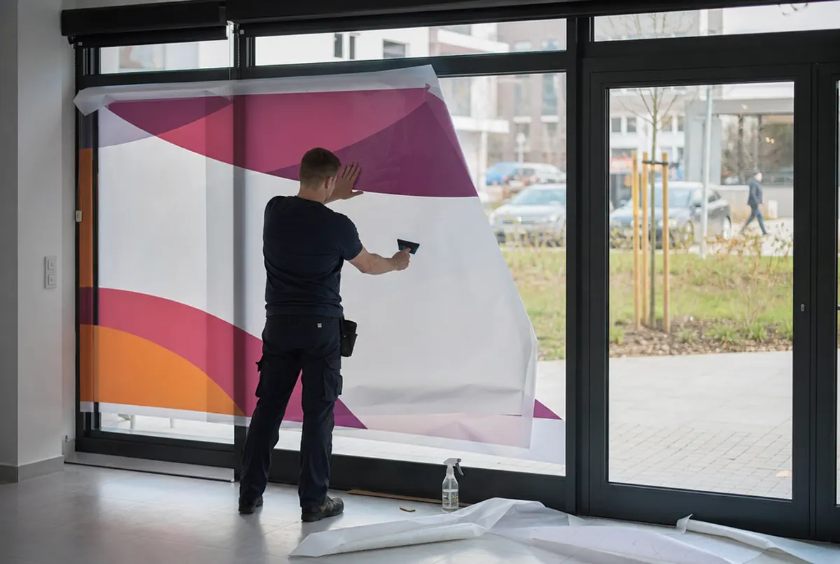 Installer applying printed film to a shop window with a squeegee