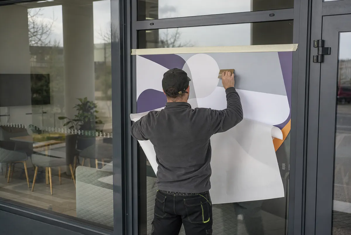 Person applying vinyl to a glass door using the hinge method