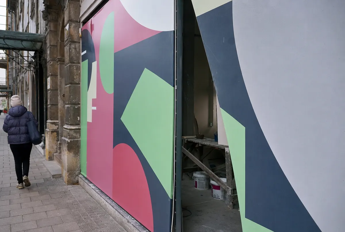 Abgeklebtes Schaufenster mit einer Grafik, die die Eröffnung ankündigt
