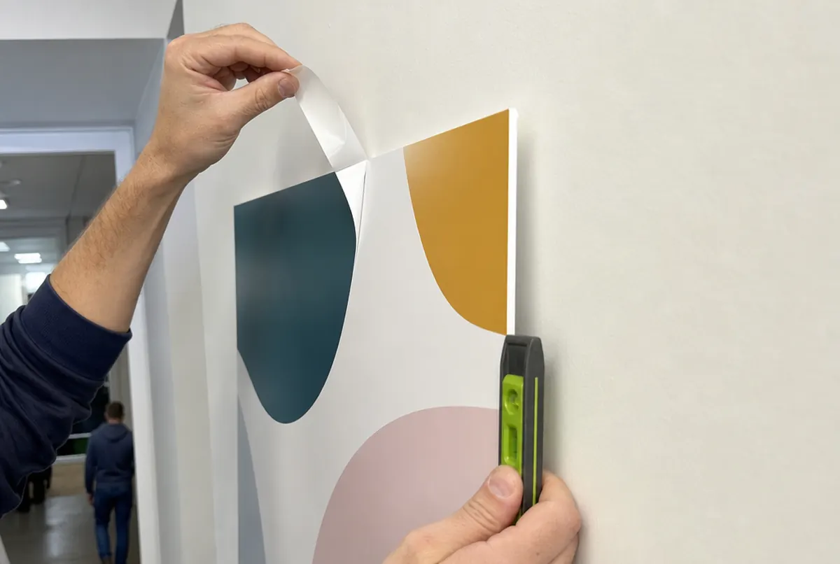 Hands fixing an A3 poster printed on PVC board to a wall