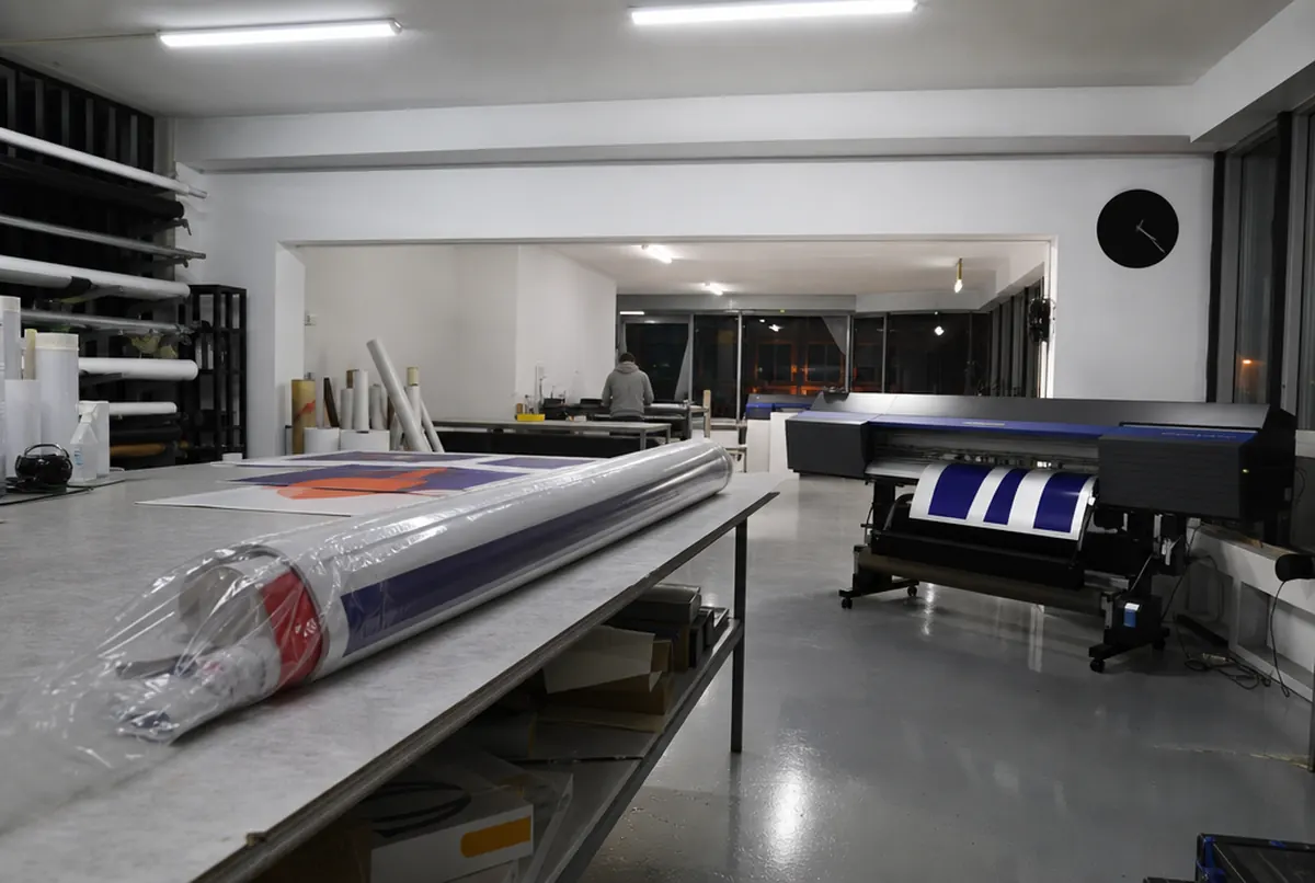 A print shop at night with a machine running and a finished order
