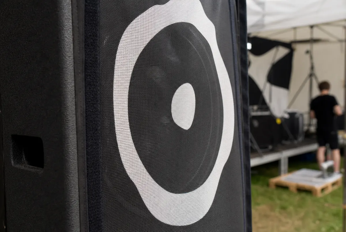 Open-weave acoustic fabric over a speaker cabinet, the driver faintly visible through it