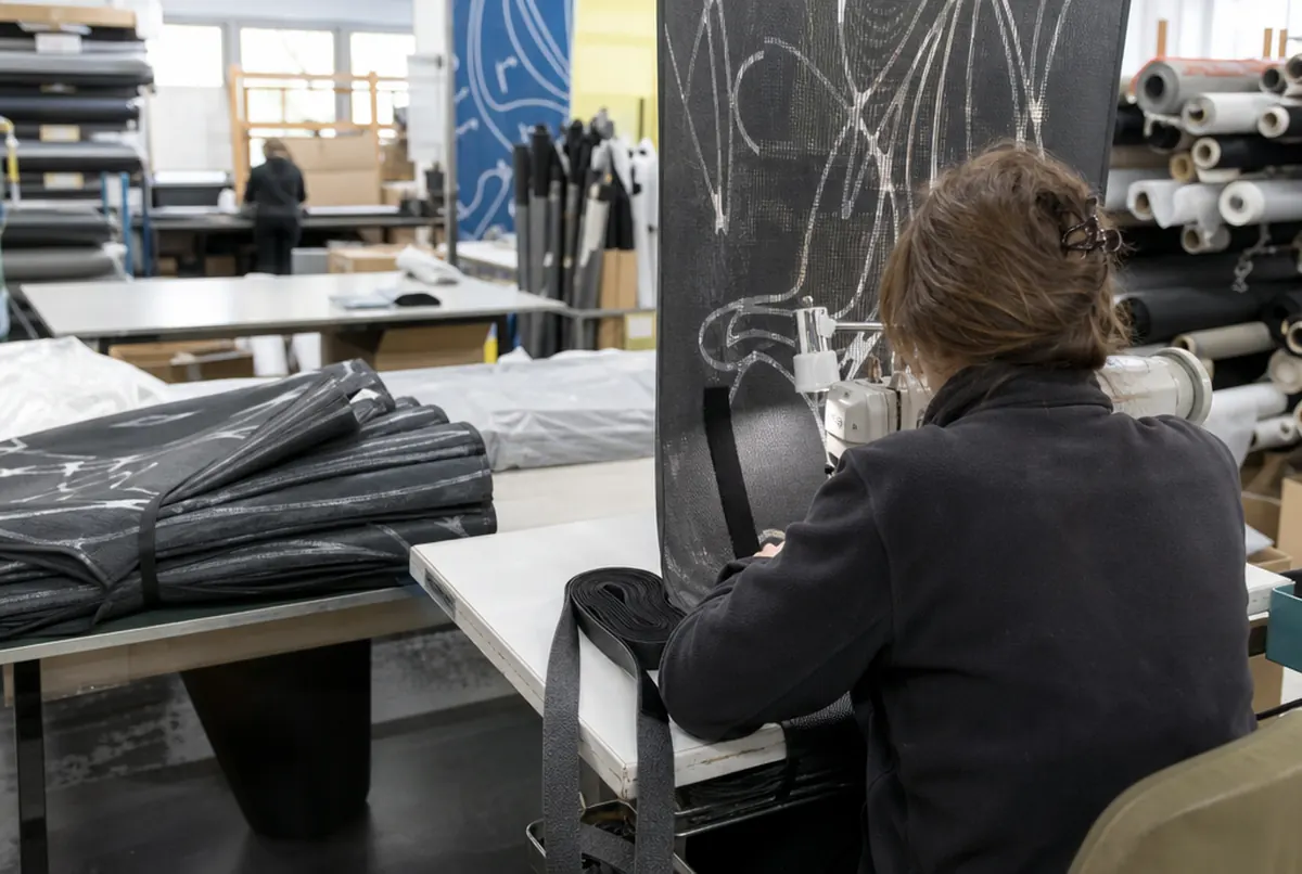Sewing velcro strips onto an acoustic mesh cover on a workshop table