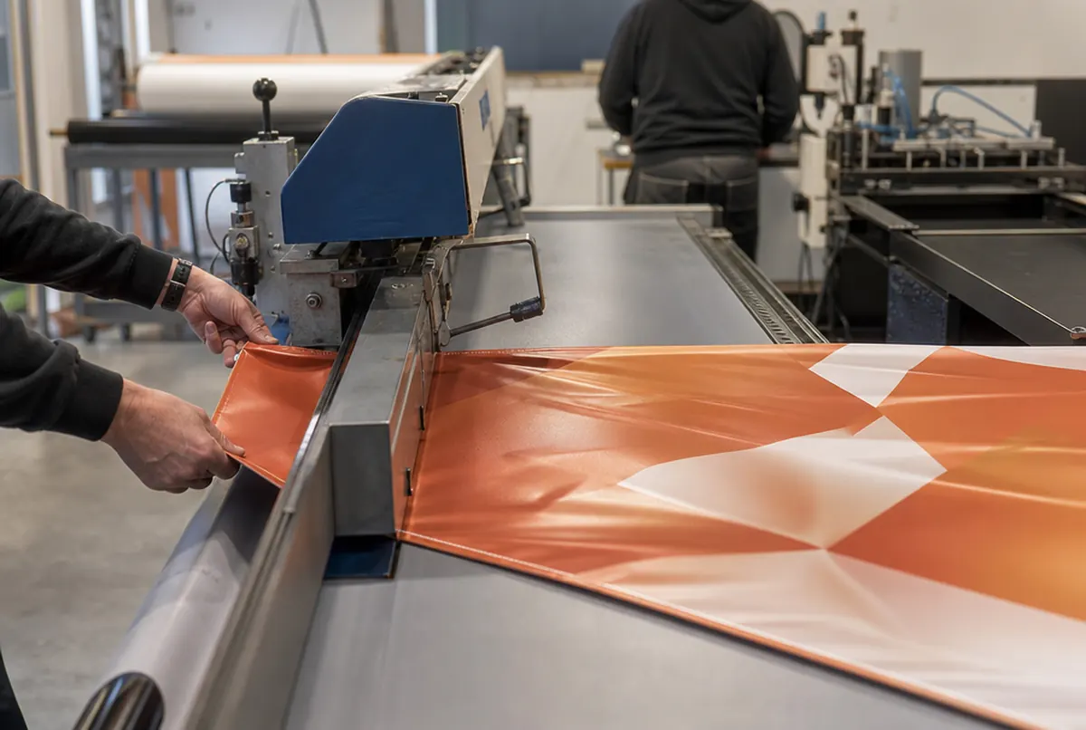 Hemming a banner edge and punching grommets every 50 cm in the print shop