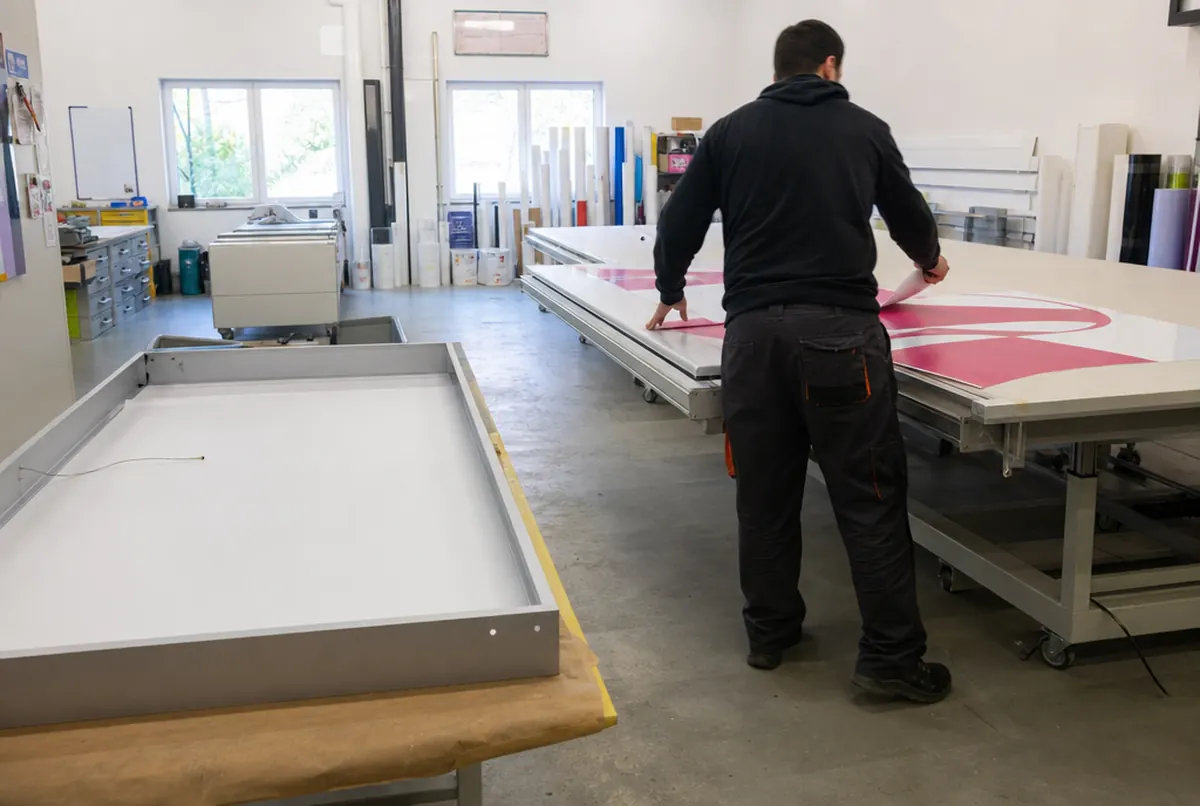 Applying printed backlit film to a milky acrylic face on an applicator table