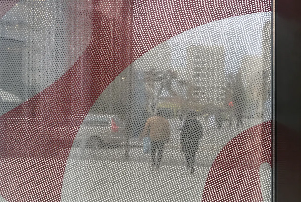 Close-up of OWV film on glass: hole grid over the print and the street seen through it