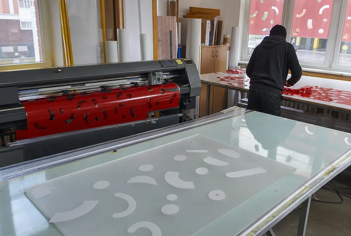 Plóter cortando formas en vinilo translúcido rojo, retirada del sobrante