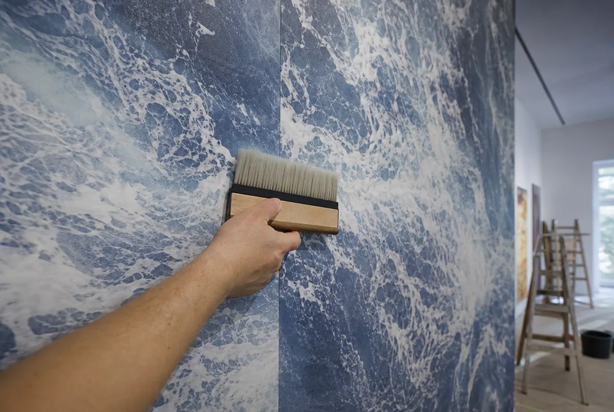Mano alisando la unión de dos tiras de fotomural con el dibujo casado