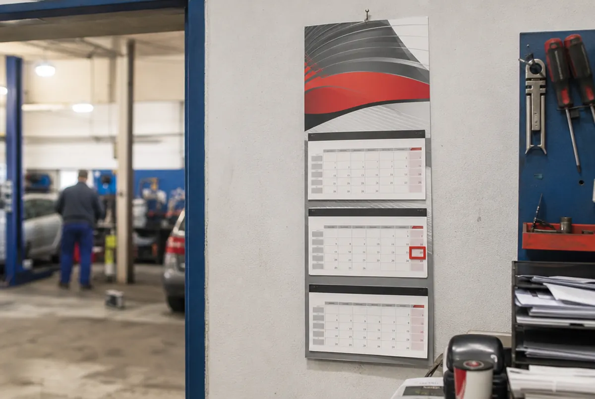 Three-part wall calendar with a printed header and date marker in a workshop office