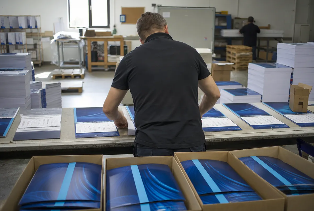 Assembling three-part calendars by attaching pads to the backing boards