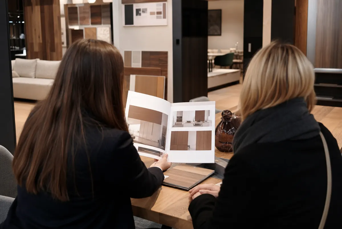 Commercial présentant un catalogue A4 ouvert à un client dans un showroom