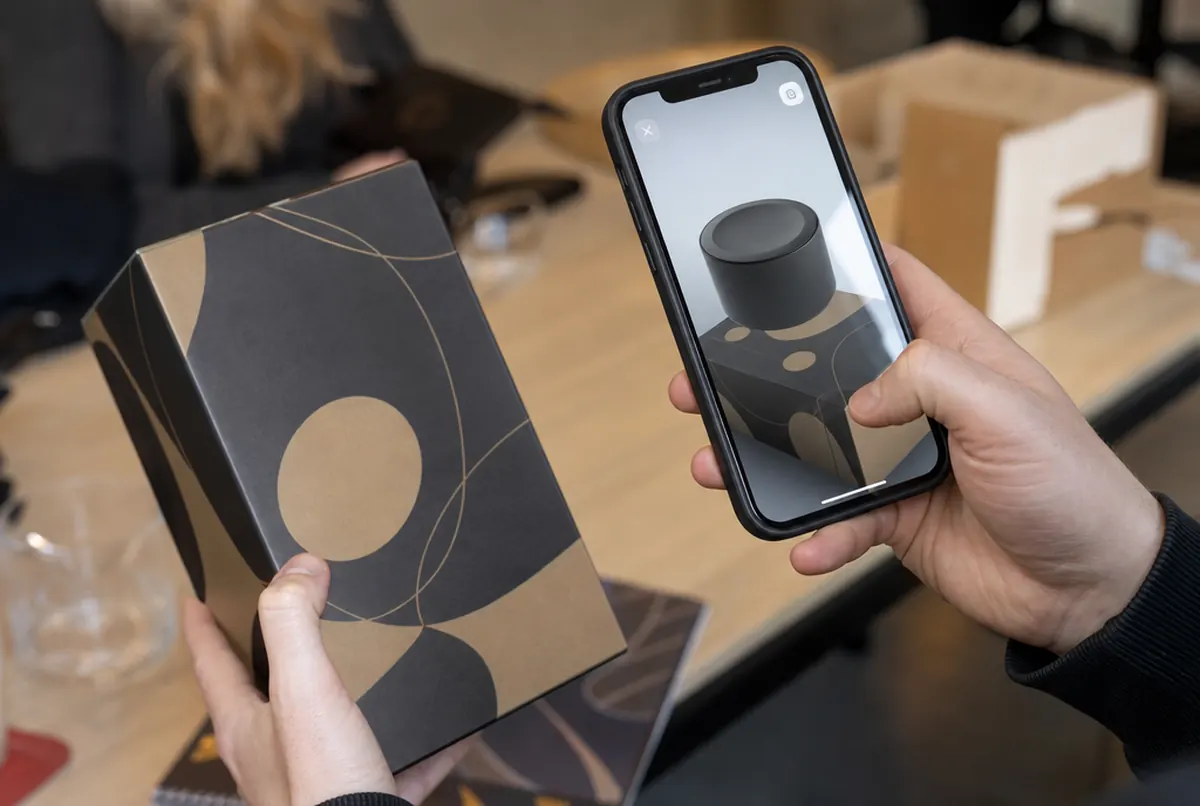 Close-up: a phone displays a 3D product model above a scanned package