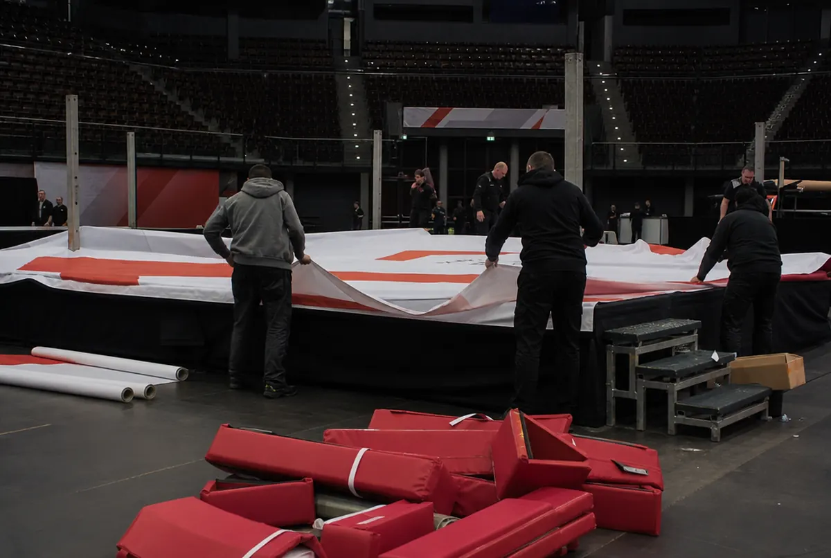 L'équipe tend une bâche imprimée sur le ring de boxe avant le gala