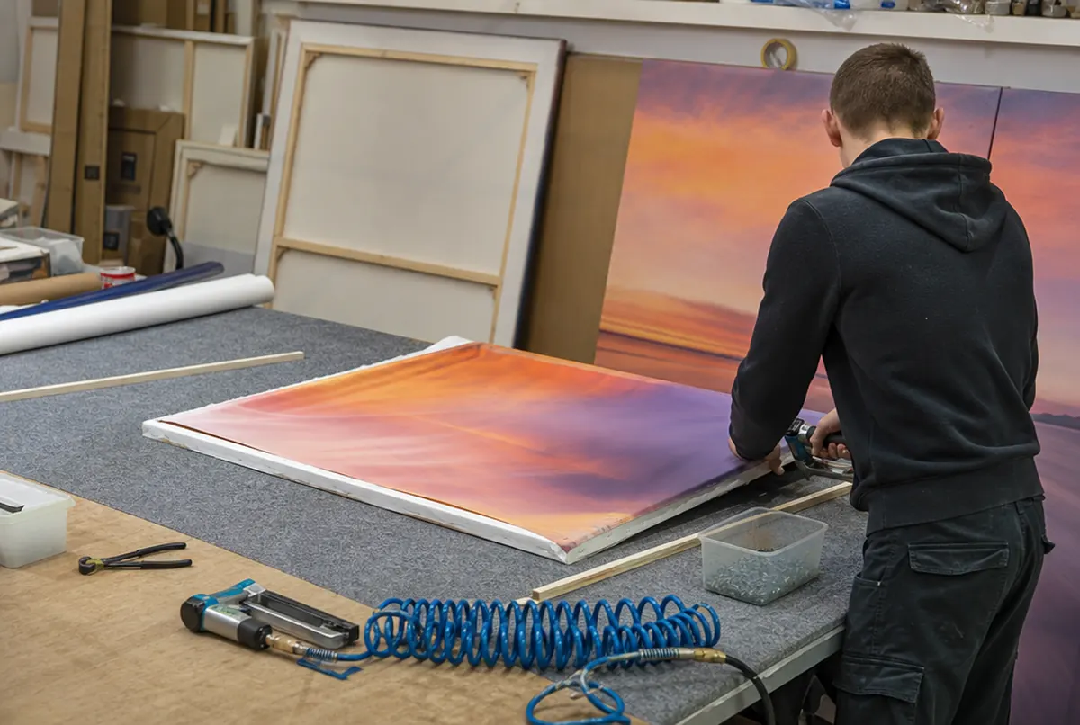 Stretching a printed canvas over a wooden frame with pliers and a staple gun