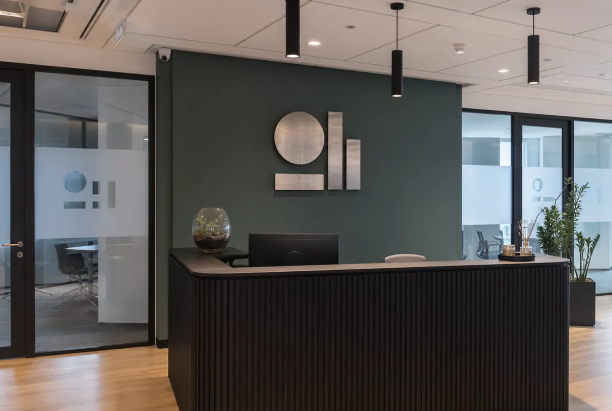 Brushed steel logo on a green reception wall and markings on the glass doors