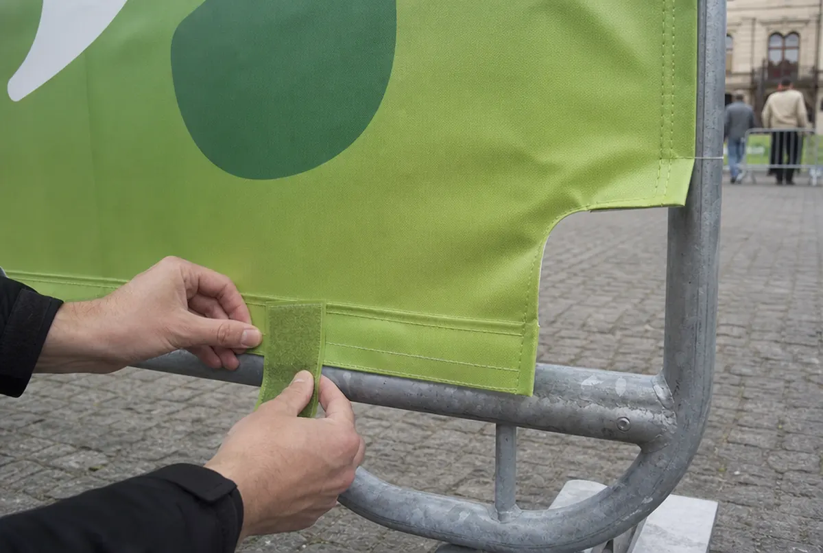 Close-up of hands fastening a barrier cover's velcro strap around the lower crossbar