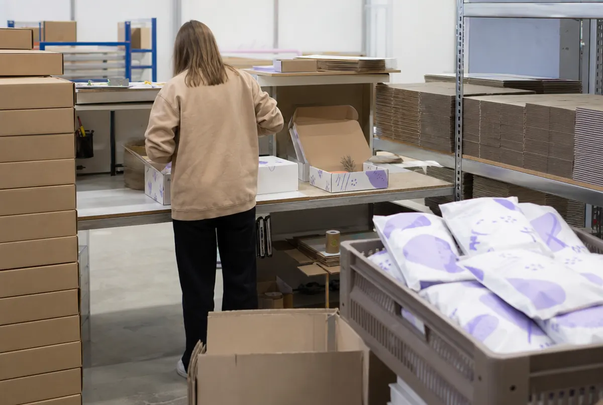 Packing station in an online store warehouse with white printed mailer boxes