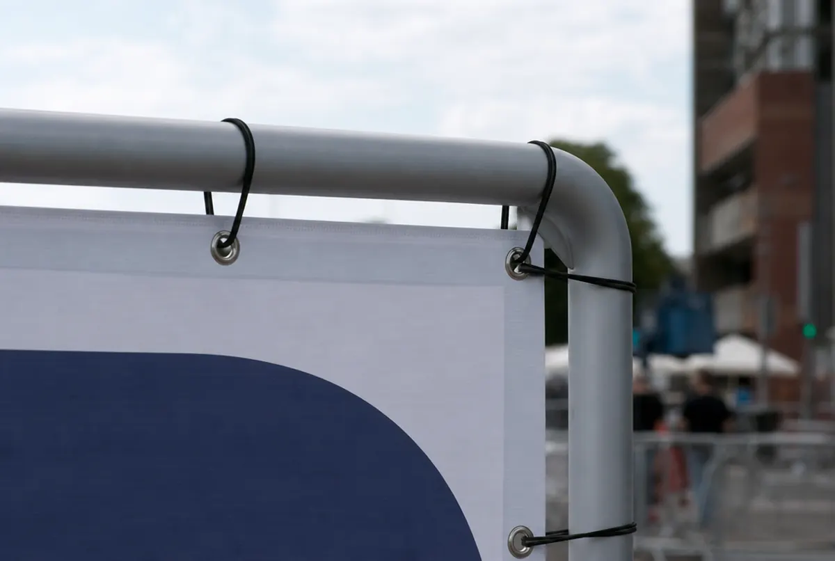 Back of a tension frame corner: banner grommets pulled taut with elastic cords