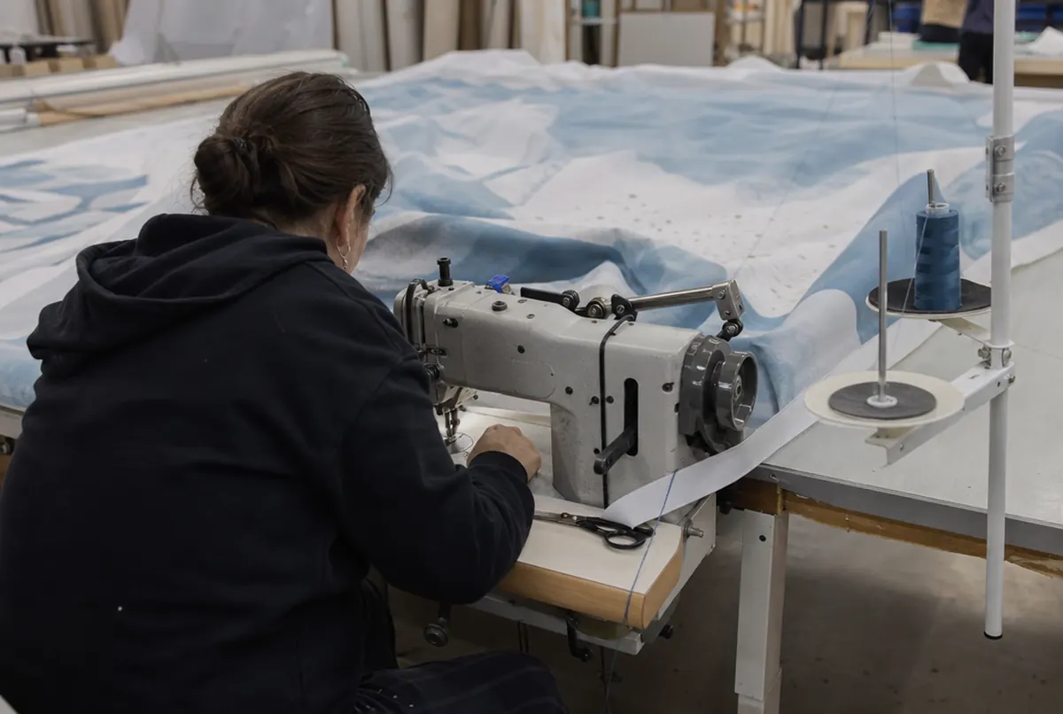 Sewing a silicone strip around the edge of a printed fabric in the workshop
