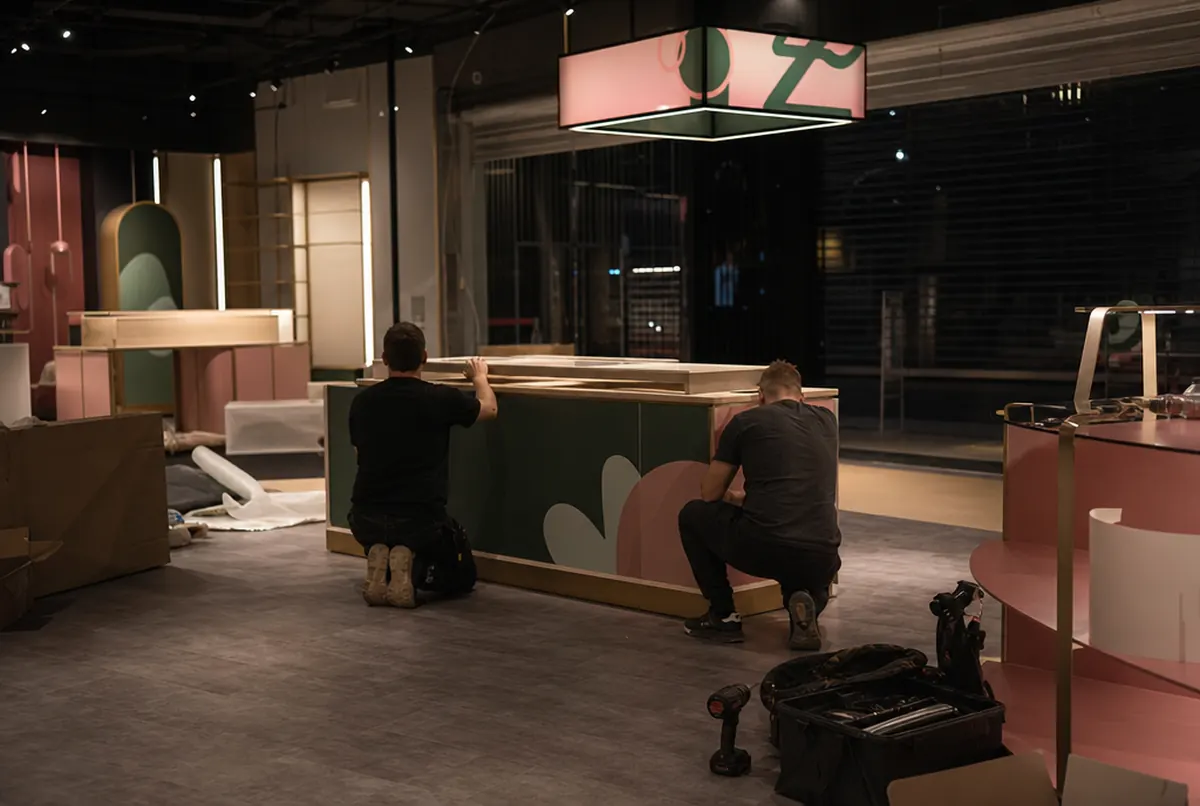Montage de nuit d'un îlot de présentation dans un magasin fermé de galerie