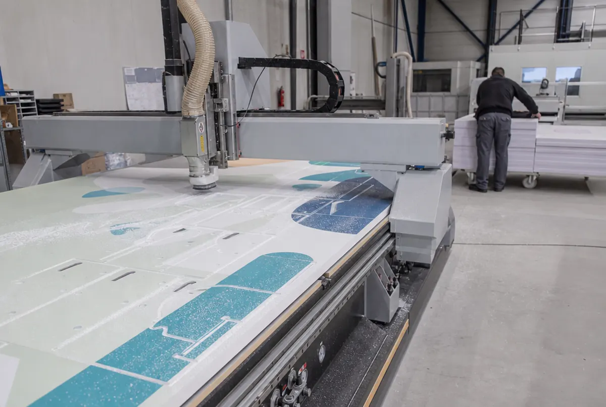 CNC router cutting hook holes into a printed PVC board for display stands