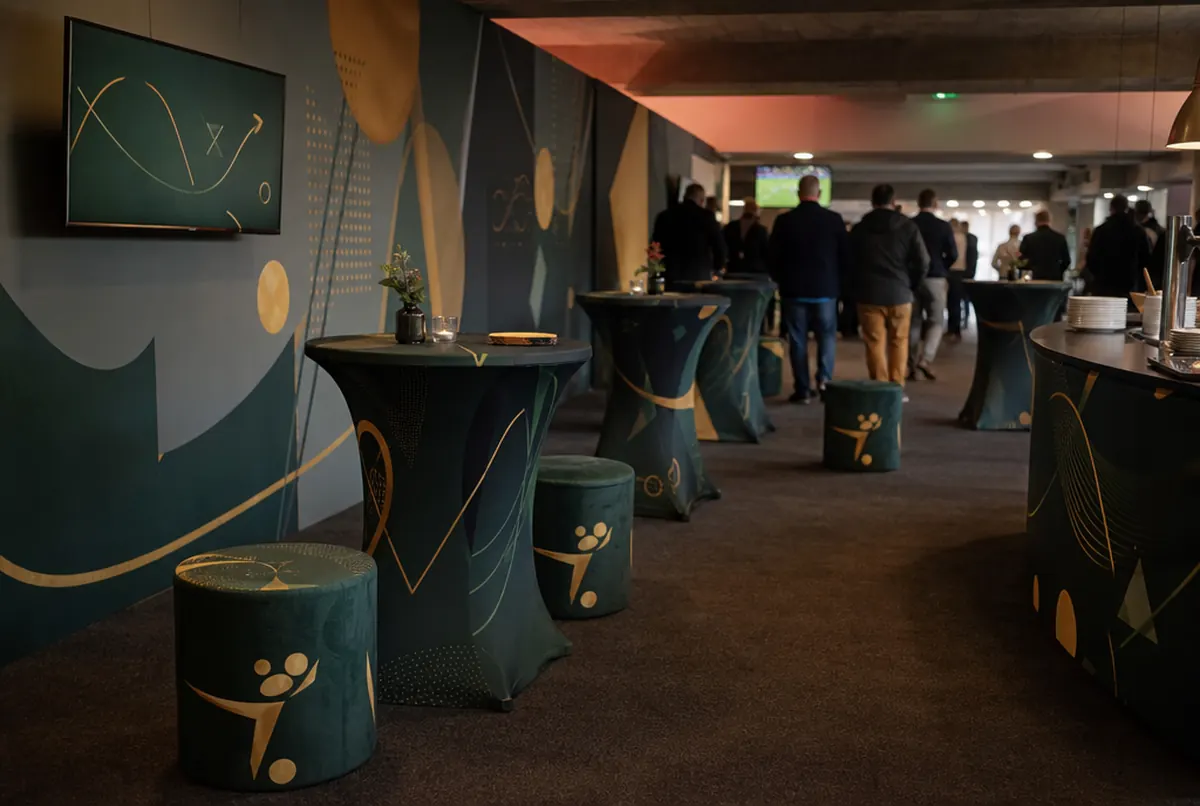 Salon VIP avec mur photo, poufs et nappes imprimés dans un stade