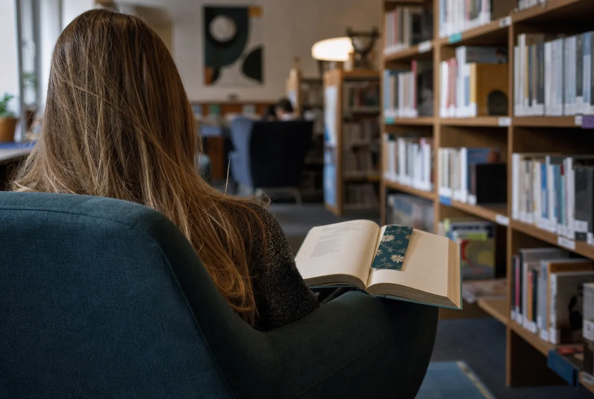 Printed bookmark in an open book of a reader in a public library