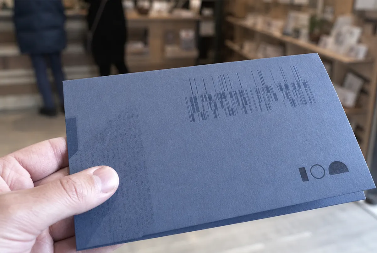 Gros plan d'un bon cadeau numéroté sur carton texturé épais, avec un rainage net