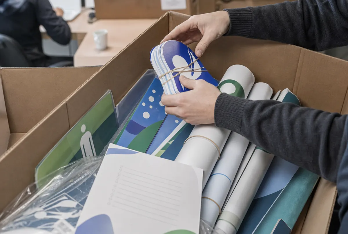 Close-up of an open campaign kit: posters, wobblers, a stand and a contents list