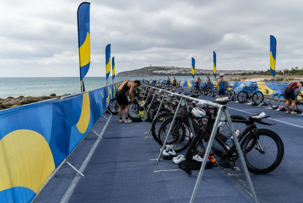 Strefa zmian zawodów triathlonowych ze stojakami na rowery i ogrodzeniem obłożonym drukowaną siatką mesh
