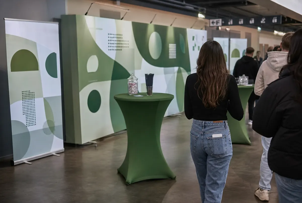 Sponsorenbereich in der Halle vor dem Spiel: grün-weiße Fotowand, Roll-ups und Stehtische mit grünen Hussen