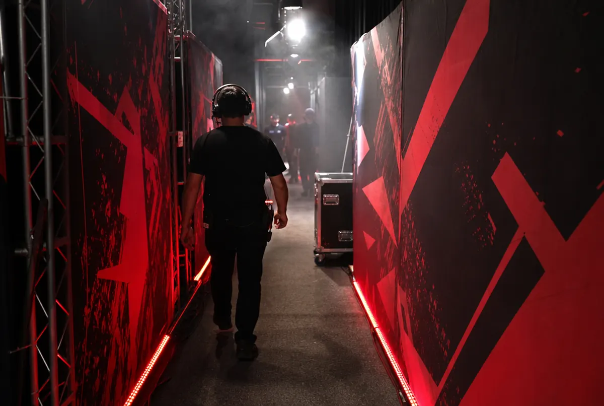 Backstage walk-out tunnel: black and red printed fabric wall panels and red LED strips along the floor