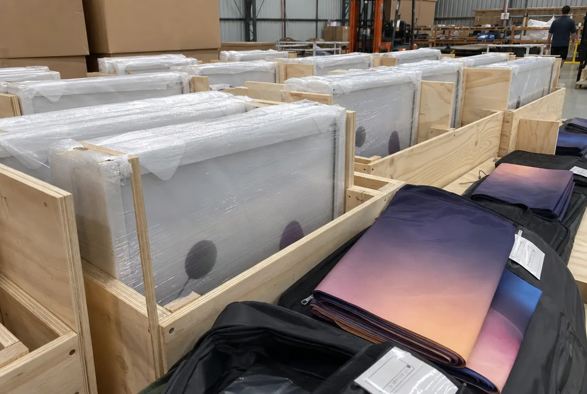 Leuchtrahmen in Schaum und Folie in Kisten sowie verpackte Stoffgrafiken, bereit für viele Filialen